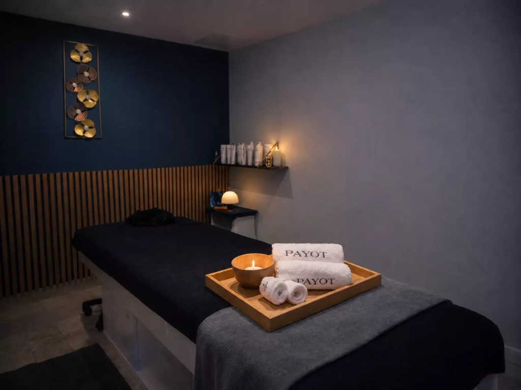 Cabine de massage cosy chez Les Fées Spa avec ambiance tamisée et serviettes Payot